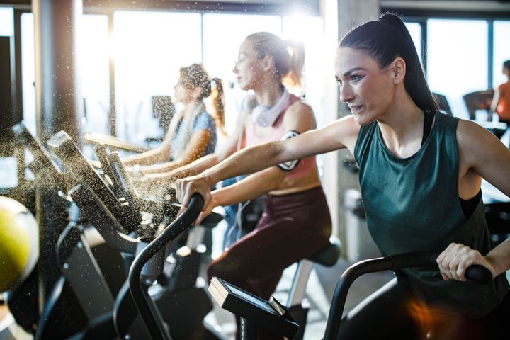 Young athletic woman feeling determined while exercising on stationary bike in a health club.