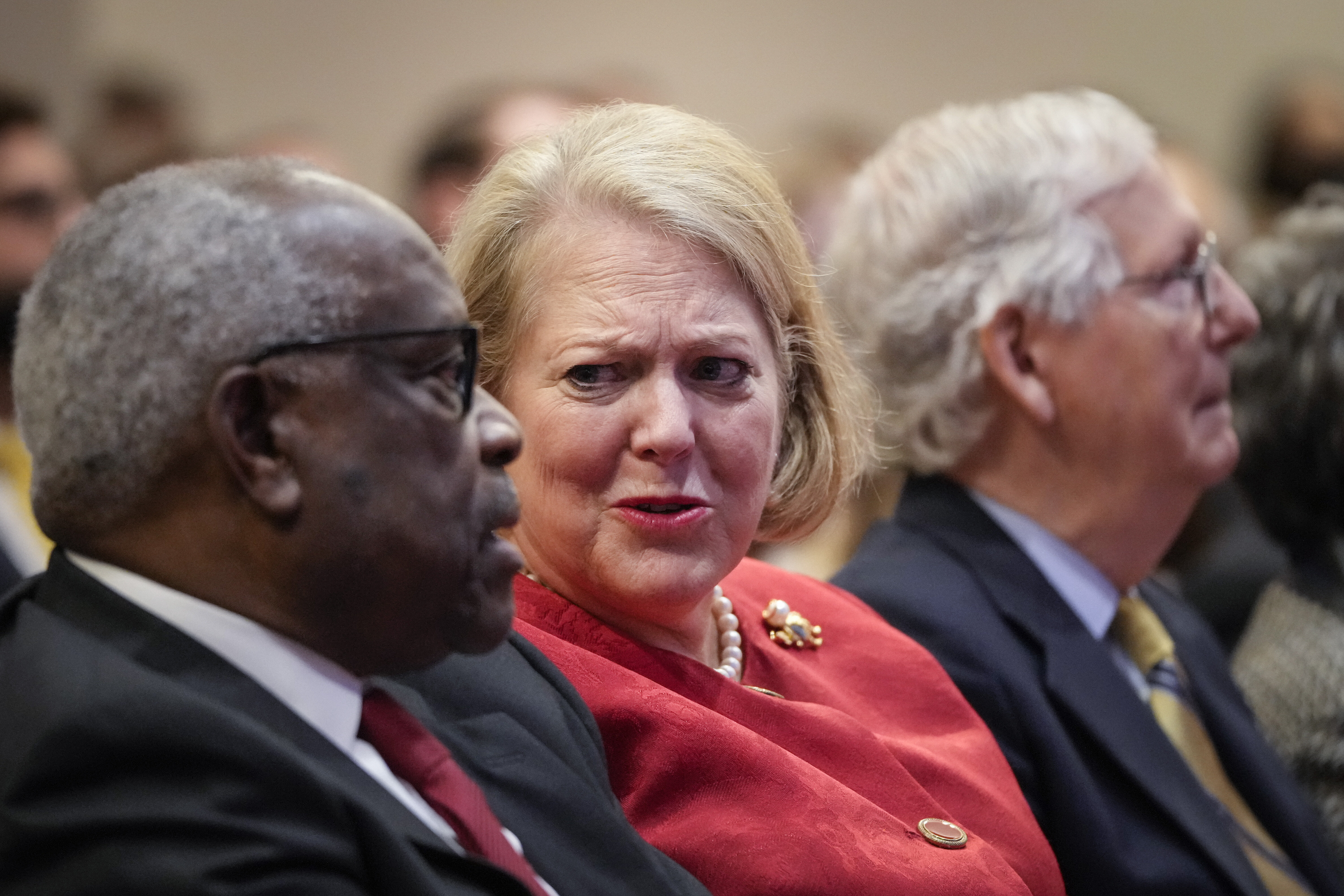 Ginni Thomas, in middle, sitting and speaking with Clarence Thomas, left.