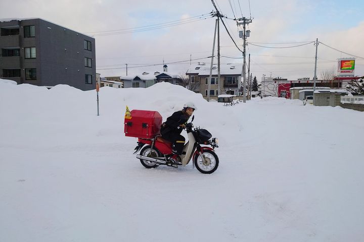 雪道に注意しながら郵便配達をする久保さん。
