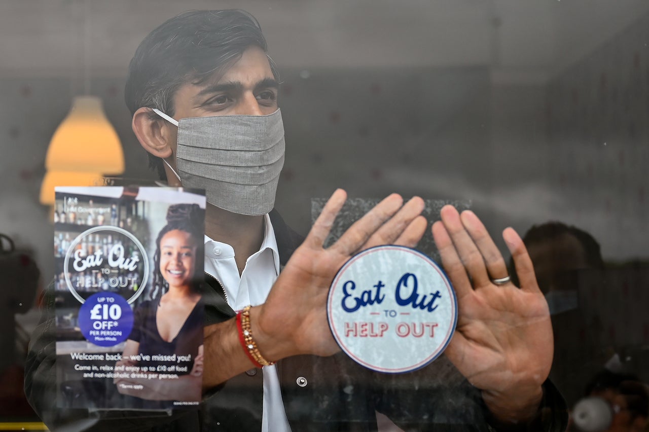 Chancellor of the Exchequer Rishi Sunak places an Eat Out to Help Out sticker in the window of a business during a visit to Rothesay on the Isle of Bute, Scotland.