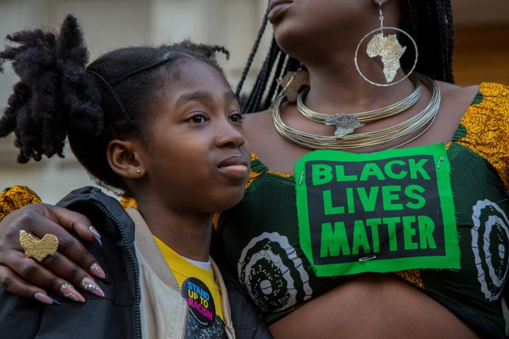 A woman wearing a BLM t-shirt embraces her child outside Hackney Town Hall during the Child Q rally. 