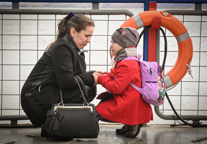 Una mujer con una niña, a punto de coger un ferry para cruzar el río Danubio en la frontera de Ucrania con Rumanía, el 25 de marzo.