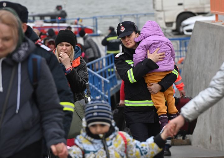 Una bombera rumana coge a una niña ucraniana en el paso de refugiados ucranianos a través del río Danubio, en la frontera rumana. 