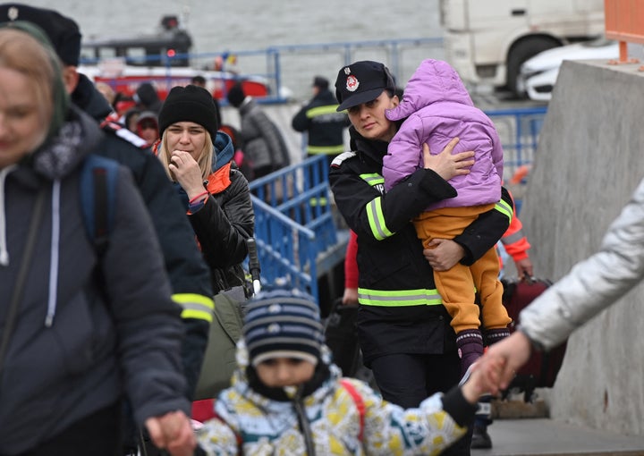 Una bombera rumana coge a una niña ucraniana en el paso de refugiados ucranianos a través del río Danubio, en la frontera rumana.