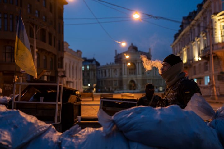 A Ukrainian soldier smokes as he and another soldier stand guard behind sandbags and in front of the National Academic Theatre of Opera and Ballet building, in Odesa, Ukraine, March 24, 2022. (AP Photo/Petros Giannakouris, File)