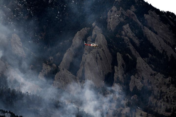 A helicopter flies above the smoke from the NCAR fire as it burns in the foothills south of the National Center for Atmospheric Research, Saturday, March 26, 2022, in Boulder, Colo. (Helen H. Richardson/The Denver Post via AP)