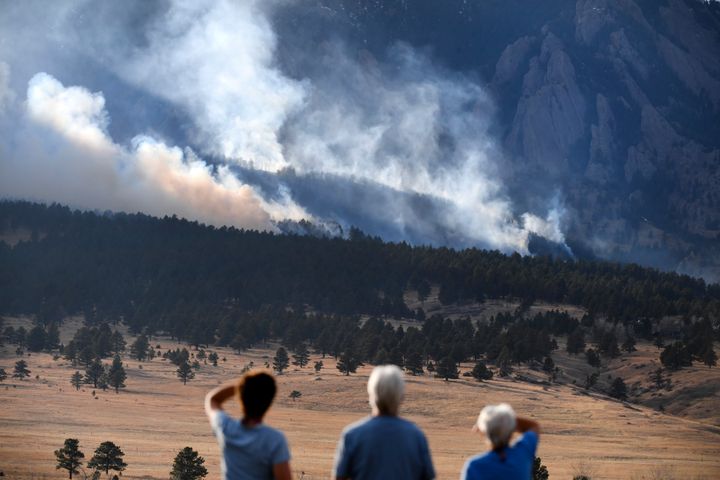 From left to right, Laura Tyson, Tod Smith and Rebecca Caldwell, residents of Eldorado Springs, watch as the NCAR fire burns in the foothills south of the National Center for Atmospheric Research, Saturday, March 26, 2022, in Boulder, Colo. (Helen H. Richardson/The Denver Post via AP)