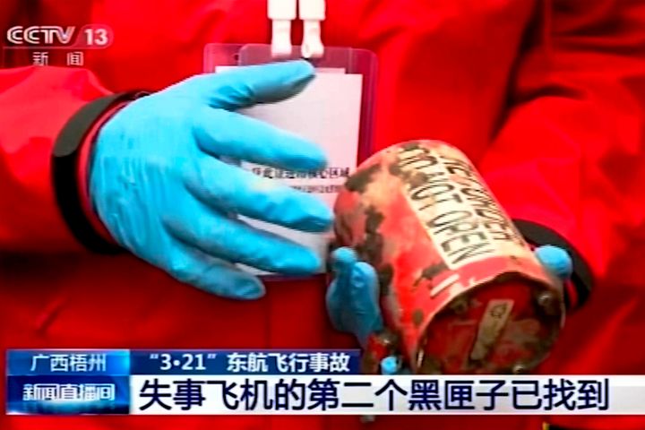 In this image taken from video footage run by China's CCTV, a search and rescue worker holds the second orange-colored "black box" recorder that was recovered at the China Eastern flight crash site in Tengxian County on Sunday.