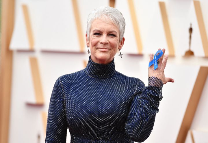 Jamie Lee Curtis wears a ribbon on her hand reading "#WithRefugees" while attending the 94th Oscars.