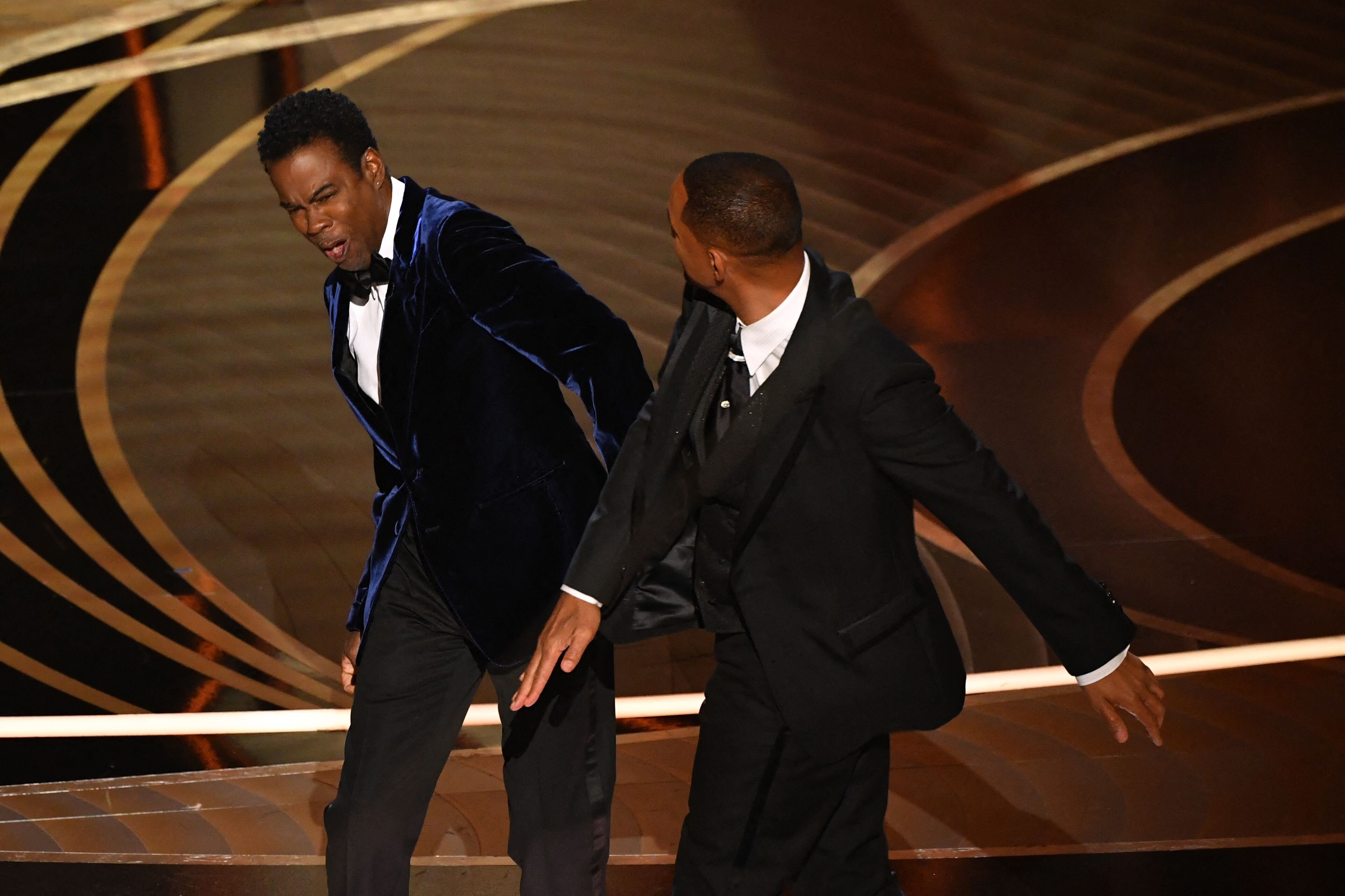 Chris Rock, left, reacts after Will Smith, right, hits him on stage at the Oscars.