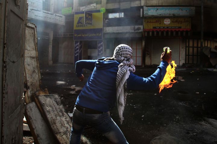 A Palestinian protester throws a Molotov cocktail towards Israeli soldiers during clashes in the West Bank city of Hebron, April 3, 2013.
