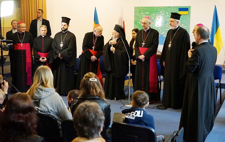 Ο πνευματικός ηγέτης των Ορθοδόξων Χριστιανών, ο Οικουμενικός Πατριάρχης Βαρθολομαίος Α', ο Πολωνός Αρχιεπίσκοπος Στάνισλαβ Γκαντέτσκι, ο επικεφαλής της Διάσκεψης των Πολωνών Επισκόπων και άλλοι κληρικοί συναντώνται με Ουκρανούς πρόσφυγες στη Βαρσοβία, Πολωνία, 29 Μαρτίου 2022. Ο Βαρθολομαίος κατήγγειλε την εισβολή της Ρωσίας στην Ουκρανία ως μια «αποτρόπαια» πράξη που προκαλεί τεράστια δεινά, ενώ ο Γκαντέτσκι προχώρησε ακόμη παραπέρα, λέγοντας ότι φέρει «τα χαρακτηριστικά της γενοκτονίας». (Γραφείο Τύπου της Διάσκεψης Πολωνών Επισκόπων)