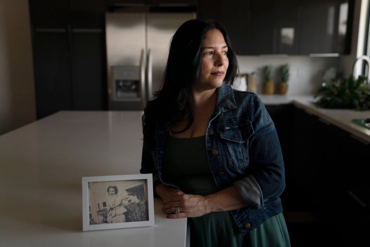 Stacy Cordova, whose aunt was a victim of California's forced sterilization program that began in 1909, stands for a photo next to a framed photo of her aunt, Mary Franco, Monday, July 5, 2021, in Azusa, Calif.