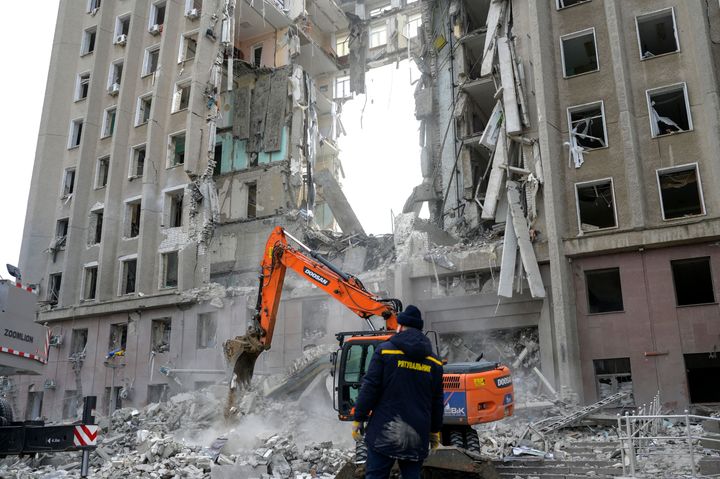 A worker watches an excavator clearing the rubble of a government building hit by Russian rockets in Mykolaiv, Ukraine on March 29, 2022.