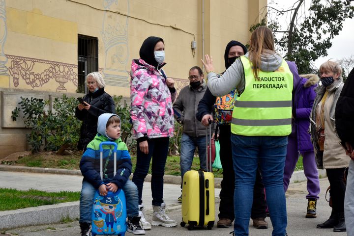 Varios refugiados ucranianos hablan con una traductoria frente al Palacio Victoria Eugenia de Barcelona, reconvertido en centro de recepción, el 18 de marzo. 