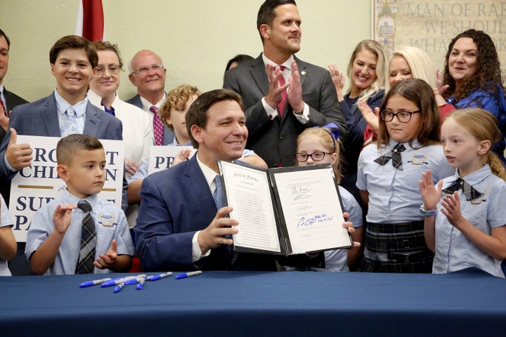 Florida Gov. Ron DeSantis displays the signed "Don't Say Gay" bill, flanked by elementary school students during a news conference on March 28, 2022, at Classical Preparatory school in Shady Hills.