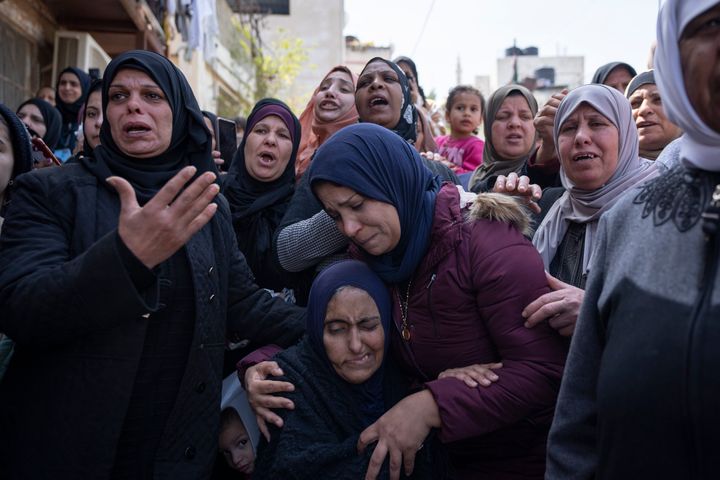 Palestinian Manal Abu Atiyeh, sitting center, is comforted by relatives during the funeral of her son Sanad Abu Atiyeh, 17, in the West Bank refugee camp of Jenin, Jenin, Thursday, March 31, 2022. Israeli forces raided a refugee camp in the occupied West Bank early Thursday, setting off a gun battle in which two Palestinians were killed and 15 were wounded, the Palestinian Health Ministry said. (AP Photo/Nasser Nasser)