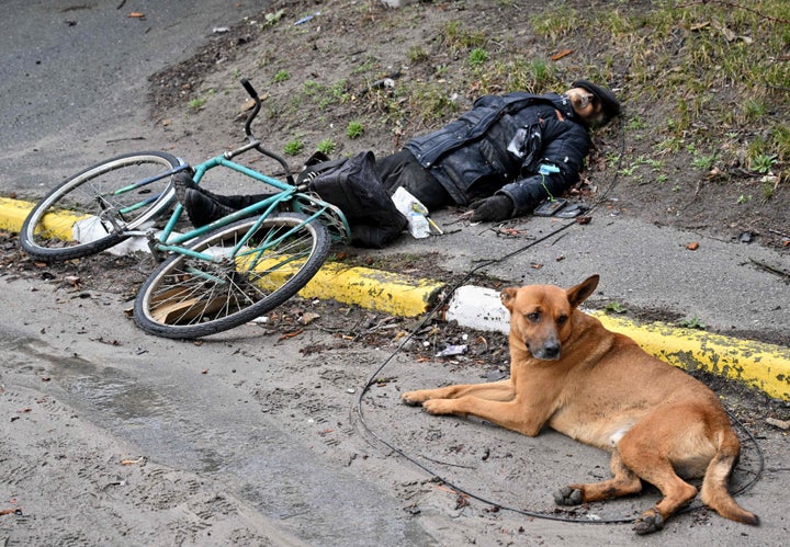 A dog lies next to a body of a man in a street in the town of Bucha, not far from the Ukrainian capital of Kyiv, on April 3.