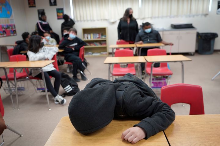 An unidentified student rests on his desk as the Mojave Unified School District Superintendent Katherine Aguirre, center rear, addresses students before their spring break at California City Middle School in California City, Calif., on March 11, 2022. 