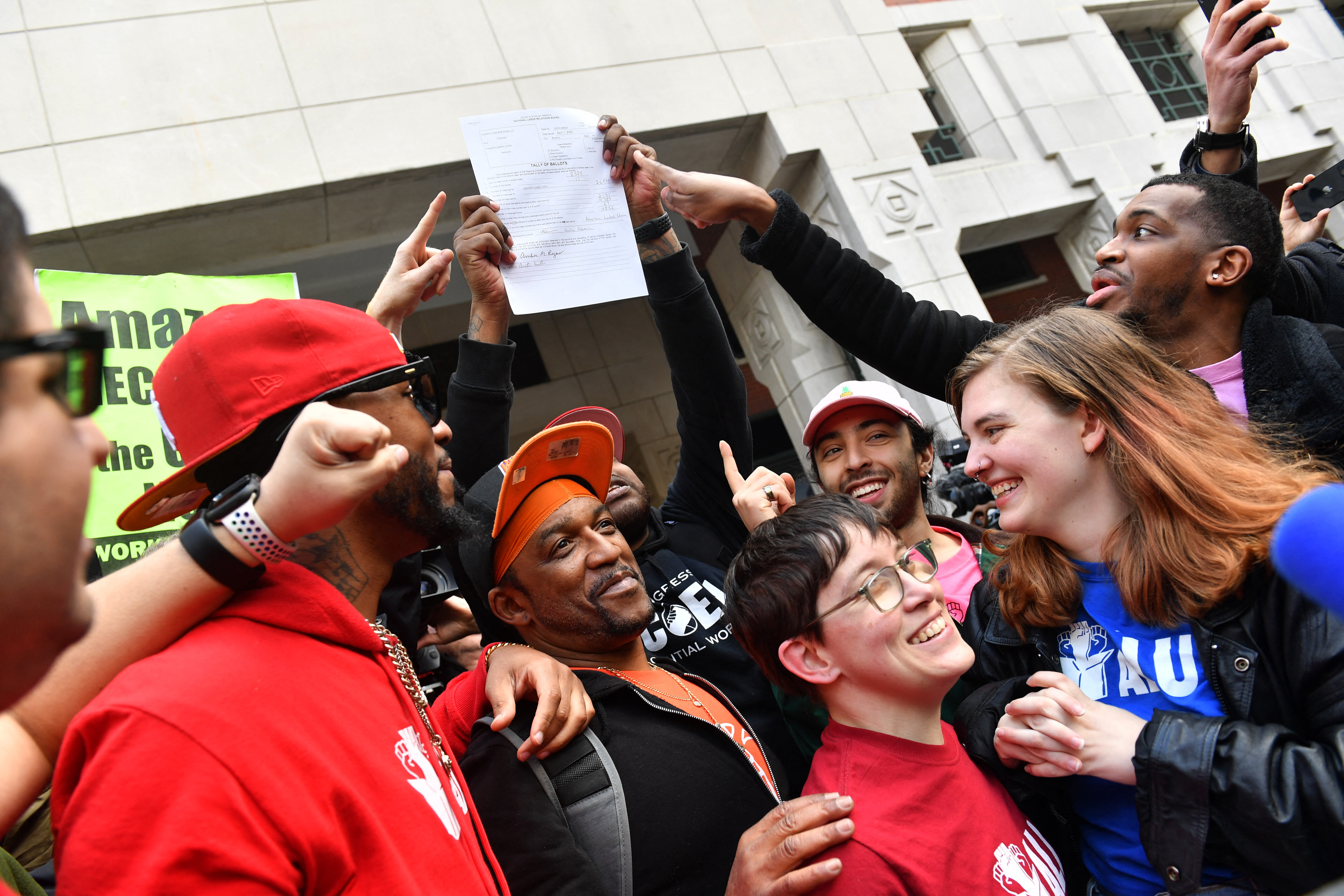 Several Amazon Labor Union members and supporters celebrate on a Brooklyn street.