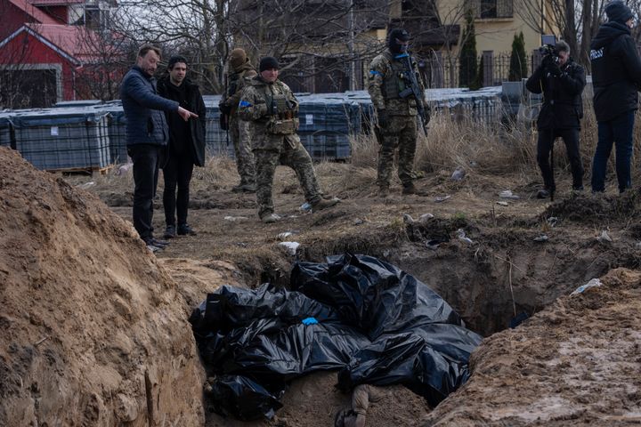 People stand next to a mass grave in Bucha, on the outskirts of Kyiv, Ukraine, on April 4, 2022. 