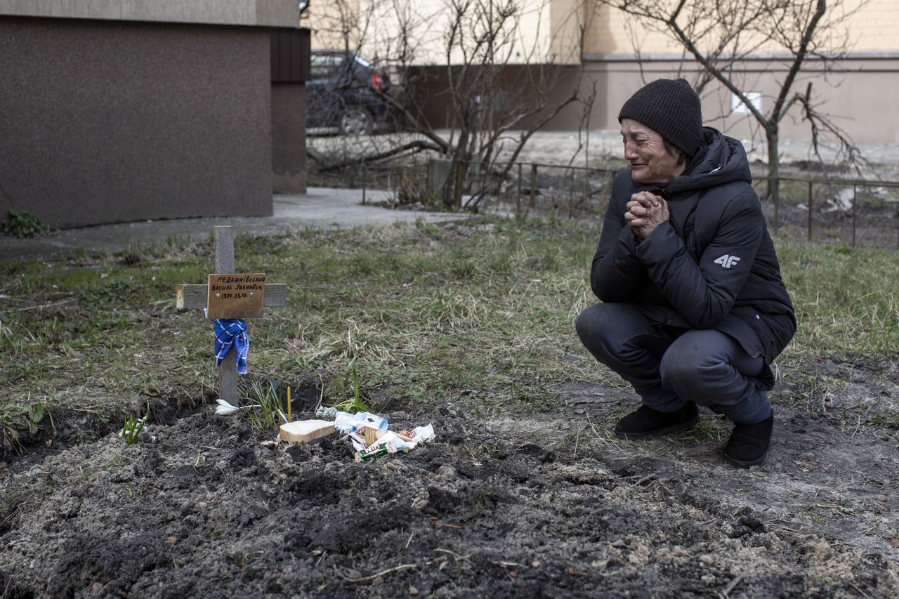 Tanya Nedashkivska, 57, grieves next to the tomb of her husband buried on the backyard of her house in Bucha, Ukraine, April 4th, 2022.