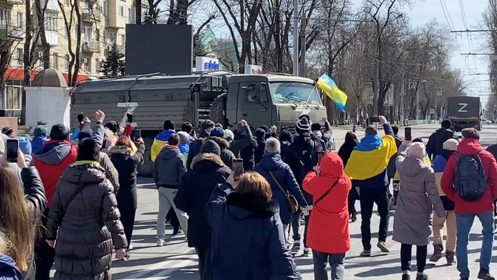 Demonstrators in occupied Kherson challenging Russian military vehicles on March 20, 2022, in still image from video obtained by Reuters.