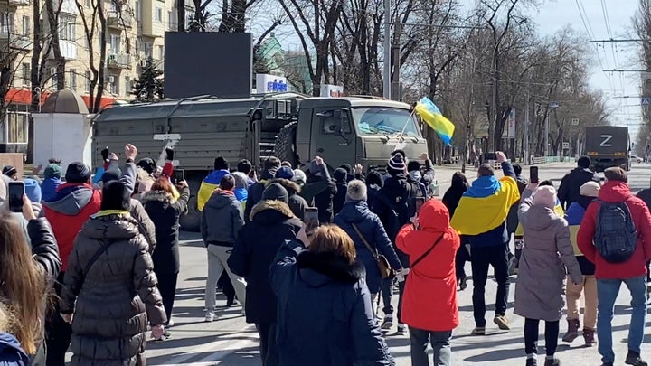 Demonstrators in occupied Kherson challenging Russian military vehicles on March 20, 2022, in still image from video obtained by Reuters.