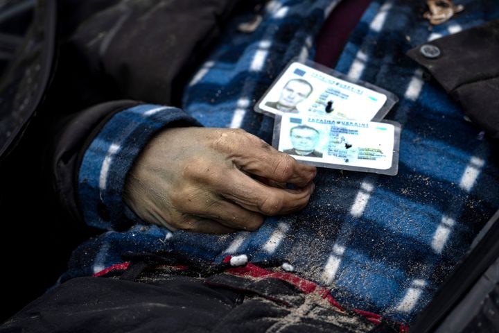 Identification cards rest on a man as policemen work to identify people following the killing of civilians in Bucha, before sending the bodies to the morgue, on the outskirts of Kyiv, Ukraine, on April 6, 2022.