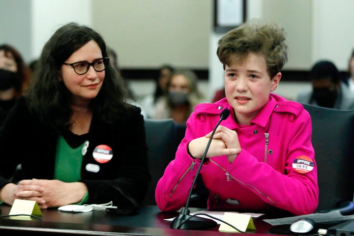 Fischer Wells, right, testifies against a bill would bar transgender girls from participating in school sports that match their gender identity, on Feb. 10, 2022, in Frankfort, Ky. Wells' mom Jenifer Alonzo listens at left.