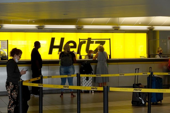 People stand at a Hertz car rental counter in the Fort Lauderdale-Hollywood International Airport in Miami, Florida. 