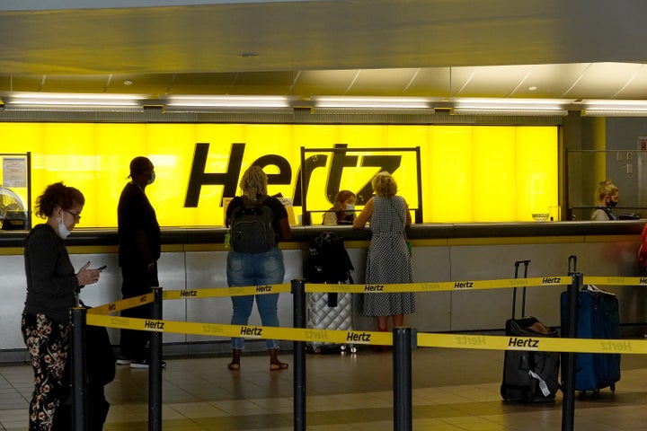 People stand at a Hertz car rental counter in the Fort Lauderdale-Hollywood International Airport in Miami, Florida.