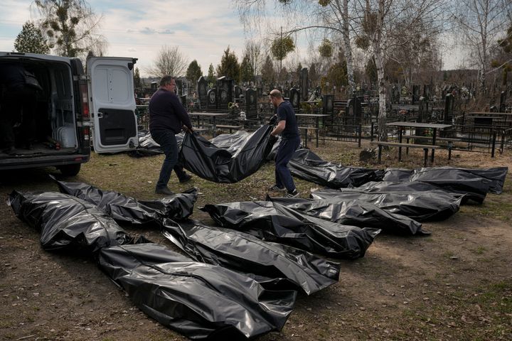 Municipal workers unload bodies from a van at a cemetery in Bucha, Ukraine on Thursday.