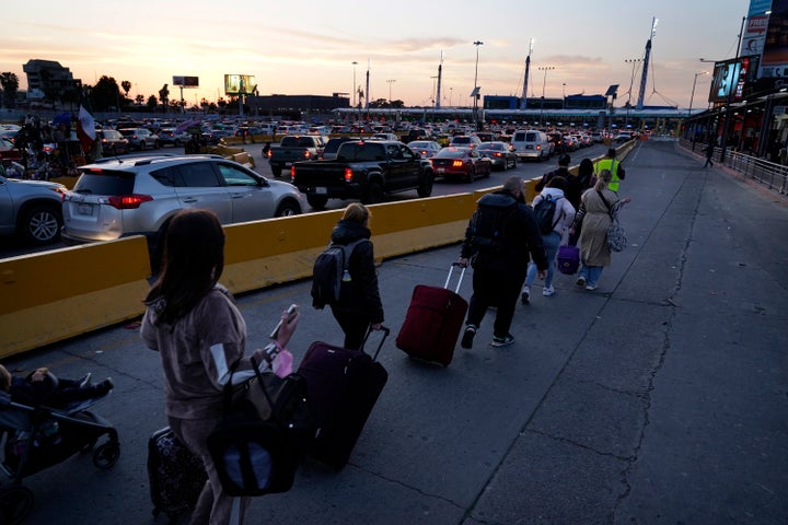 Ukrainian refugees follow a volunteer closer to the San Ysidro Port of Entry as they prepare to cross the border on April 4, 2022, in Tijuana, Mexico. About 200 to 300 Ukrainians were being admitted daily at the San Ysidro crossing this week, with hundreds more arriving in Tijuana, according to volunteers who manage the waiting list. There were 973 families or single adults waiting on Tuesday.