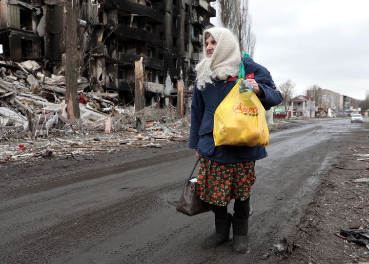 An elderly woman walks past a block of flats destroyed by Russian shelling in the city of Borodyanka.