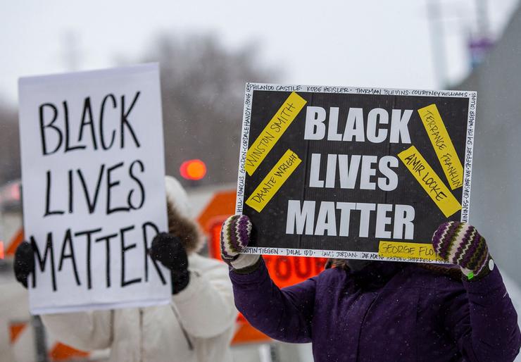 Demonstrators hold "Black Lives Matter" signs on Feb. 24 in front of the U.S. district court in St. Paul, Minnesota, where a jury found three former Minneapolis police officers guilty of violating the civil rights of George Floyd, whose May 2020 murder by police sparked nationwide protests.