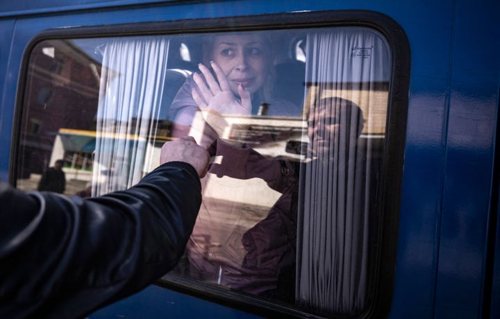 A woman waves to say good bye to her husband as she leaves on a bus, a day after a rocket attack at a train station in Kramatorsk, on April 9, 2022.
