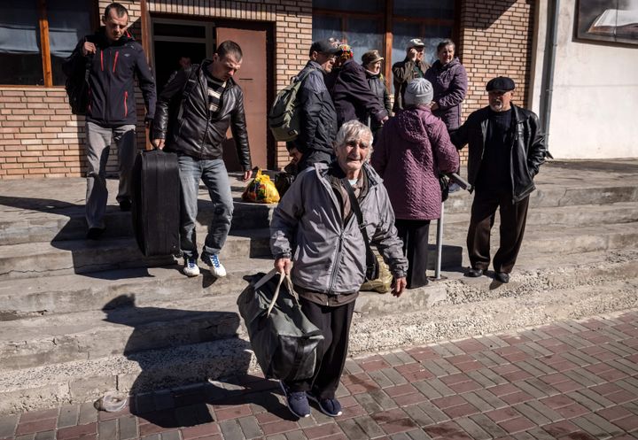 People wait for a bus with their luggage a day after a rocket attack at a train station in Kramatorsk, on April 9, 2022.