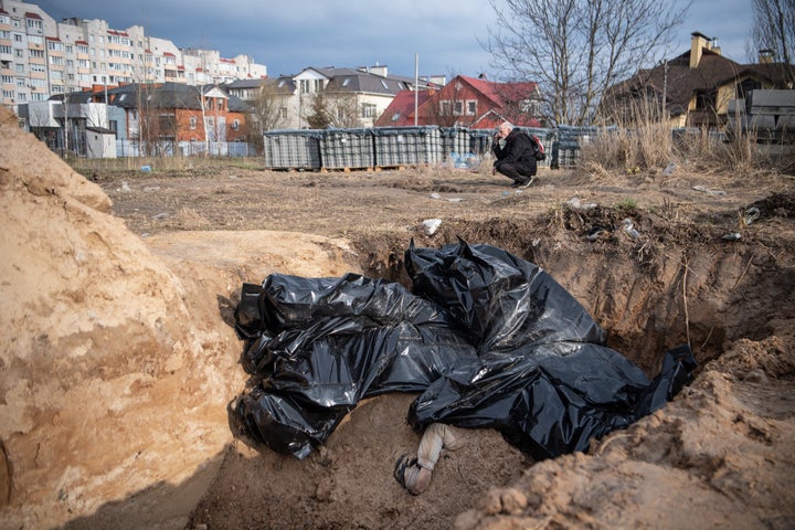 A man prays near dead bodies in body bags at a mass grave near a church in Bucha, a town near Kyiv that was recently liberated from Russian forces.