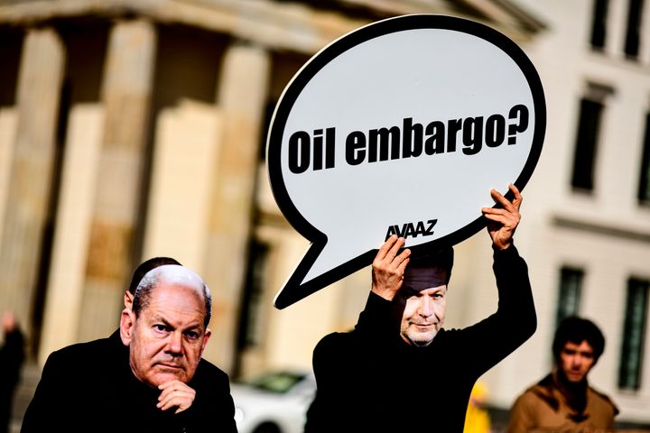 Ακτιβιστές με μάσκες που φέρουν τα πρόσωπα του Γερμανού Καγκελάριου Όλαφ Σολτς και του Γερμανού υπουργού Οικονομικών Λίντνερ, υψώνουν πλακάτ με το ρητορικό ερώτημα: Εμπάργκο στο πετρέλαιο; απαιτώντας από το Βερολίνο ταχύτερες αποφάσεις ενώ συνεχίζεται η ρωσική εισβολή στην Ουκρανία. 8 Απριλίου 2022. (Fabian Sommer/dpa via AP)