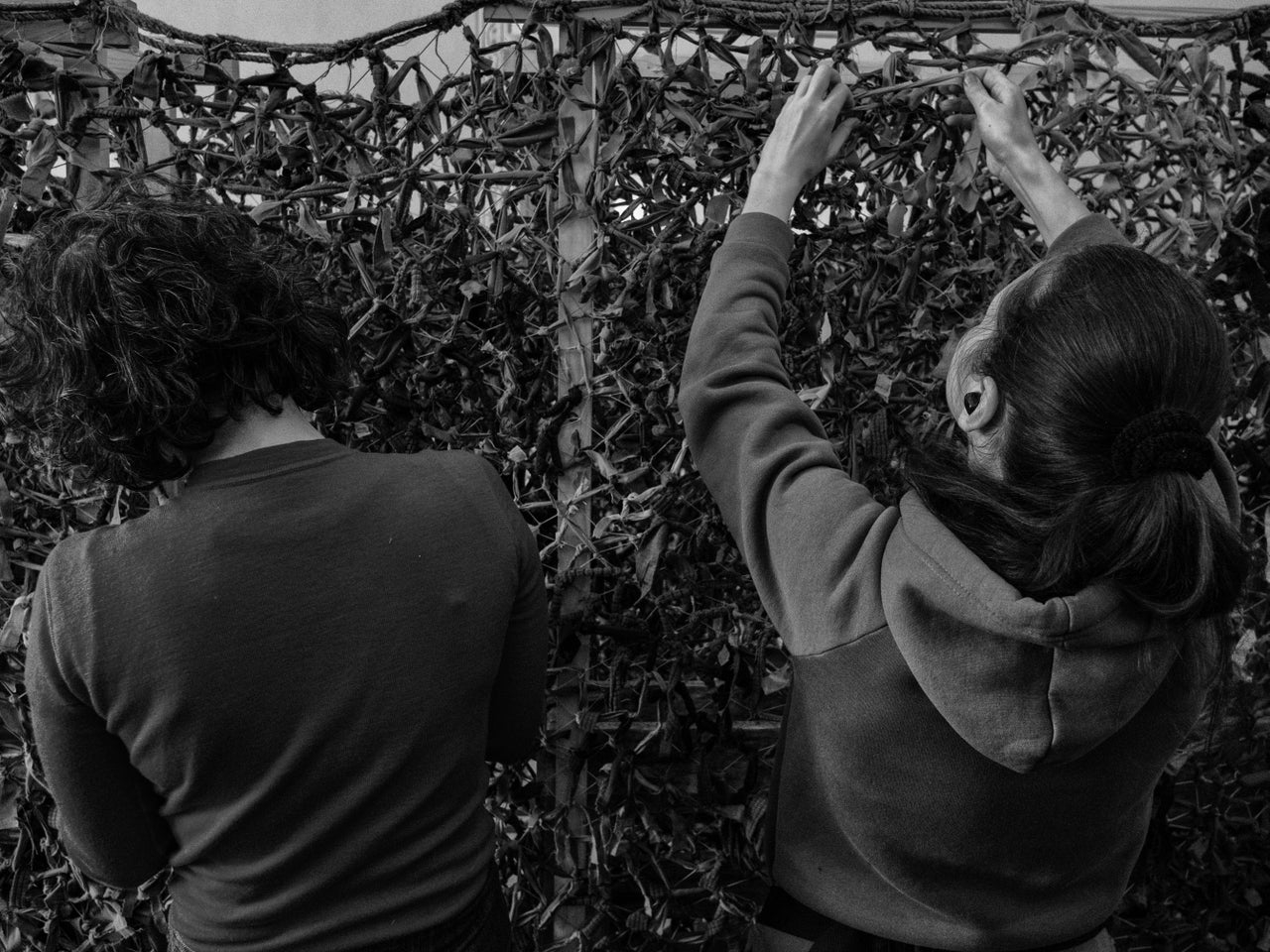 Volunteers assemble camouflage netting.