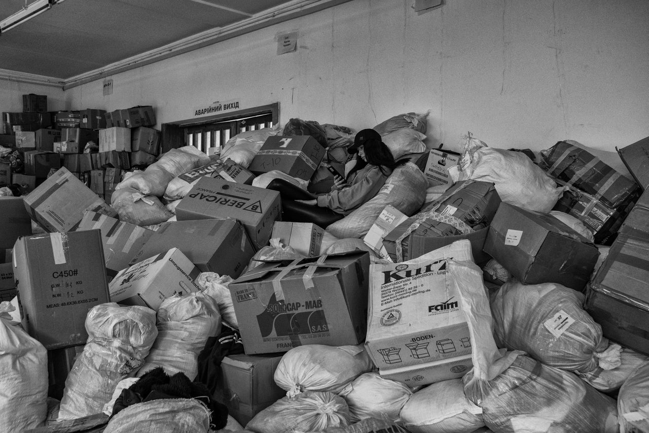 A volunteer at the main aid station in Lviv takes a break on a pile of blankets donated for civilians fleeing their homes.