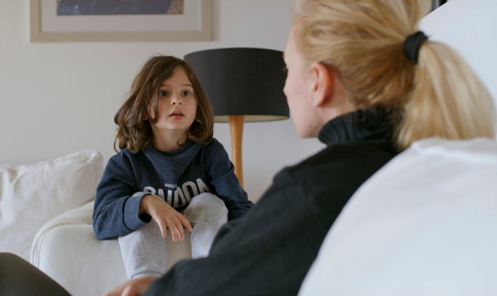 Young mother talking to her five year old son, sitting on a sofa, in the living room