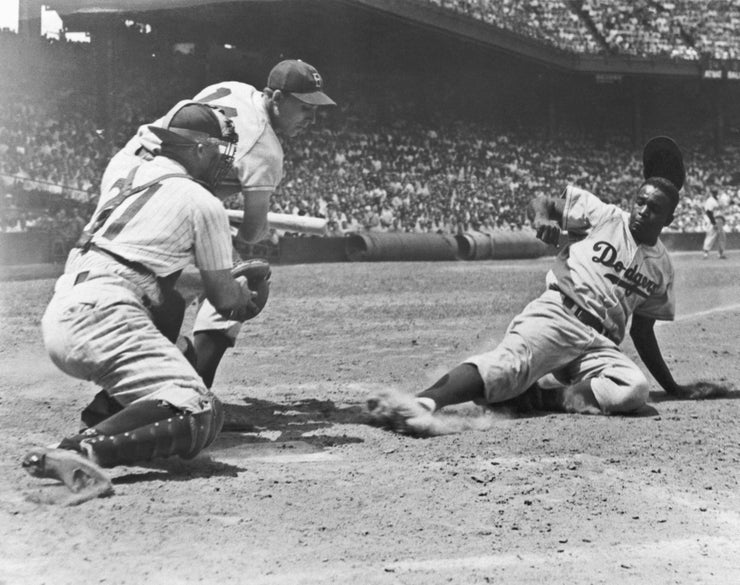 Jackie Robinson, of the Brooklyn Dodgers, slides home on a steal in the fourth inning of the first game of a double header with the Phillies on July 2, 1950.