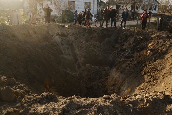 People look at a crater from an explosion in Horodnya, Ukraine on Thursday.