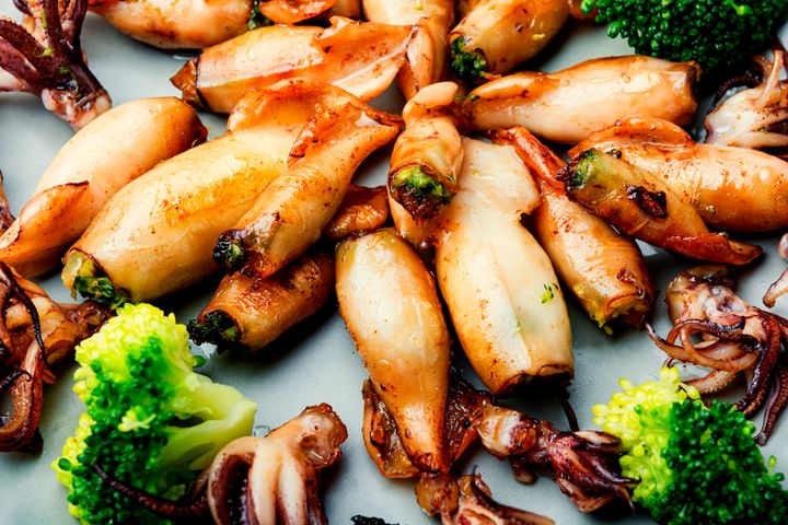 Baked squid stuffed with broccoli.Grilled calamari with vegetables.Seafood