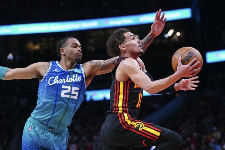 Atlanta Hawks guard Trae Young (11) drives to the basket past Charlotte Hornets forward P.J. Washington (25) during the first half of an NBA play-in basketball game Wednesday, April 13, 2022, in Atlanta.