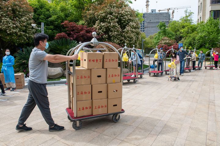 A resident delivers boxes of food which are distributed by local governament to residents in a compound during a Covid-19 lockdown, in Pudong district in Shanghai on April 15, 2022.