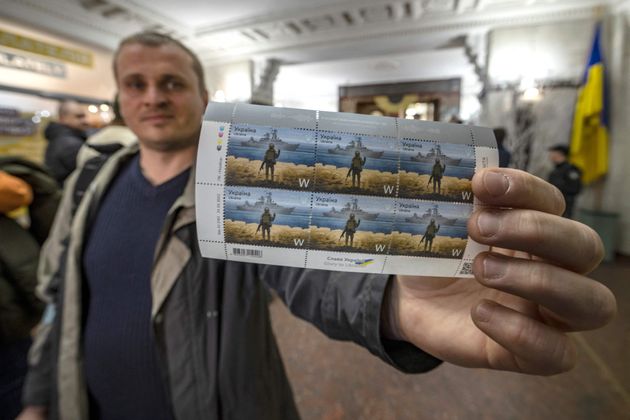 Un Ukrainien dans un bureau de poste du centre de Kiev, avec des timbres représentant un soldat...