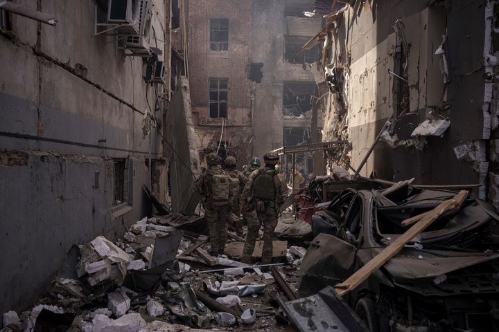 Ukrainian servicemen walk among the debris of damaged buildings after a Russian attack in Kharkiv, Ukraine, Saturday, April 16, 2022.